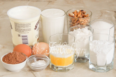 Для приготовления этого шоколадного торта нам понадобятся следующие ингредиенты: мука пшеничная высшего сорта, сахарный песок и сахарная пудра, сметана, очищенные грецкие орехи, сливочное масло (заранее растопить и остудить), куриные яйца, несладкий какао-порошок и пищевая сода