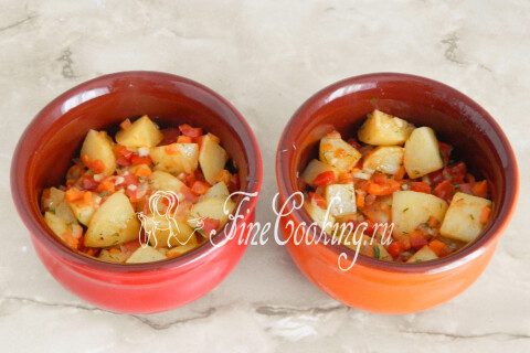 Картофель с овощами, разложенный по двум керамическим горшочкам.