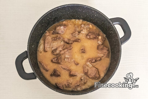 Кастрюля с мясом, накрытая крышкой, на маленьком огне.