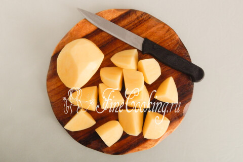 Крупные и средние клубни картофеля, нарезанные кусками на доске.